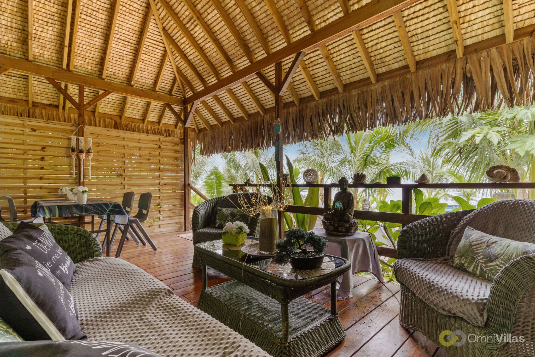Salon extérieur ombragé, sièges confortables et bois tropical.