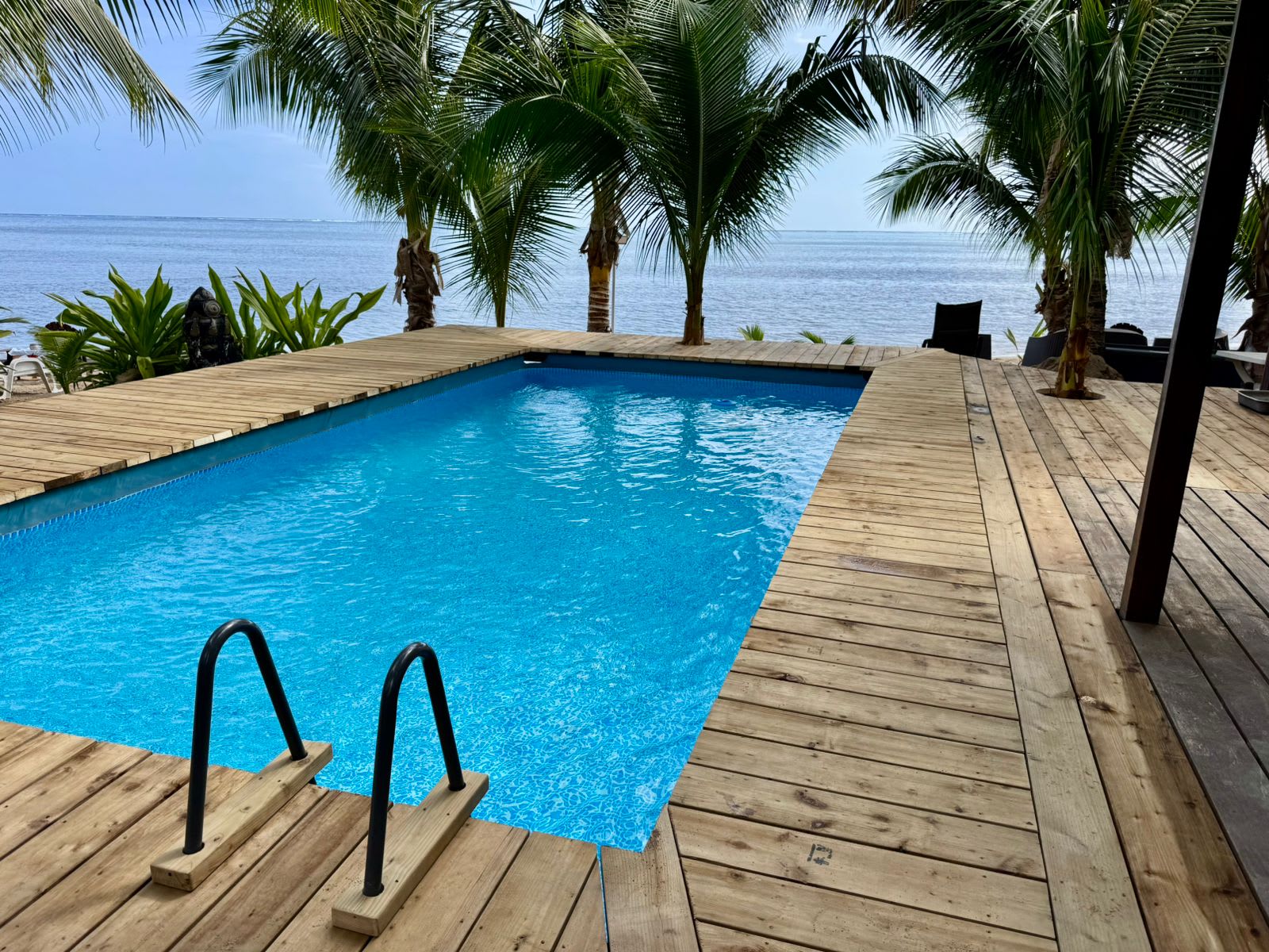 Piscine sur la terrasse à Haapiti, palmiers et lagon au-delà.
